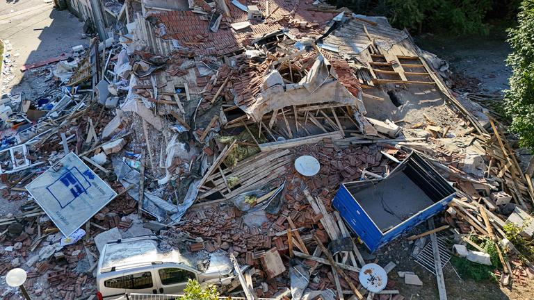 Ein eingestürztes Haus. Teile des Gebäudes liegen auf einem Auto. Das Haus ist vollständig zerstört.