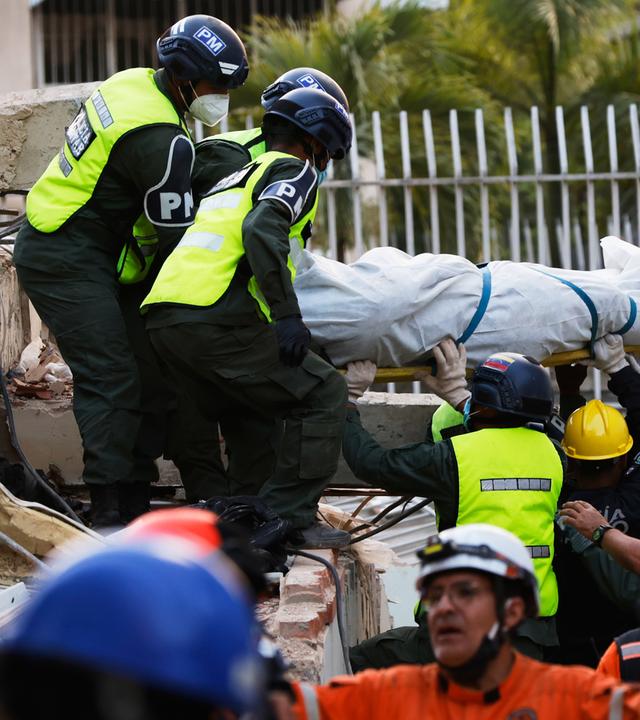 Rettungskräfte tragen eine aus den Trümmern eines eingestürzten Gebäudes in Caracas, Venezuela, geborgene Leiche weg.