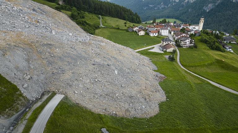 Eine Luftaufnahme zeigt eine mit dem Felssturz „Brienzer Rutsch“ bedeckte Straße im Dorf Brienz-Brinzauls, Kanton Graubünden, Schweiz.