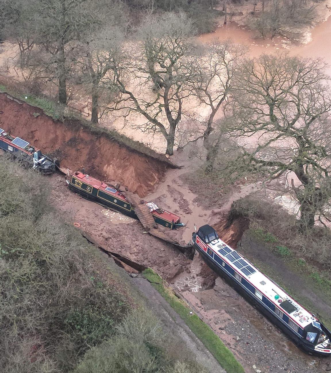 Drei Boote liegen neben einem verschlammten Kanal auf dem Trockenen, aufgerissener Erdboden.