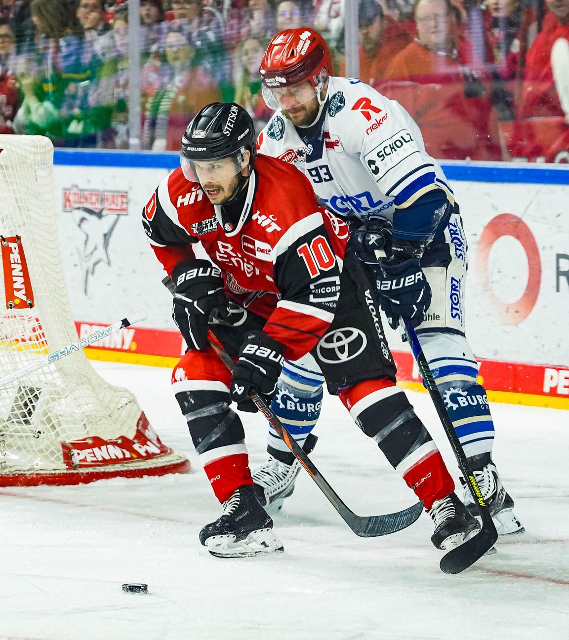Der Eishockeyspieler der Kölner Haie, Tanner Kero, führt den Puck in der Nähe des Tores der Schwenninger Wild Wings, bedrängt von Kyle Platzer.