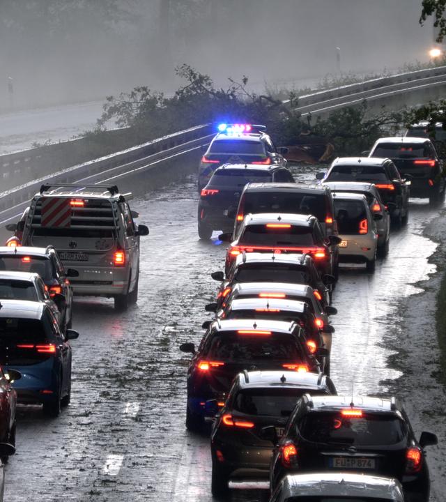 Die Polizei leitet den Verkehr auf der Bundesstraße 4 bei Erlangen-Tennenlohe an durch Unwetter umgestürzte Bäume vorbei.