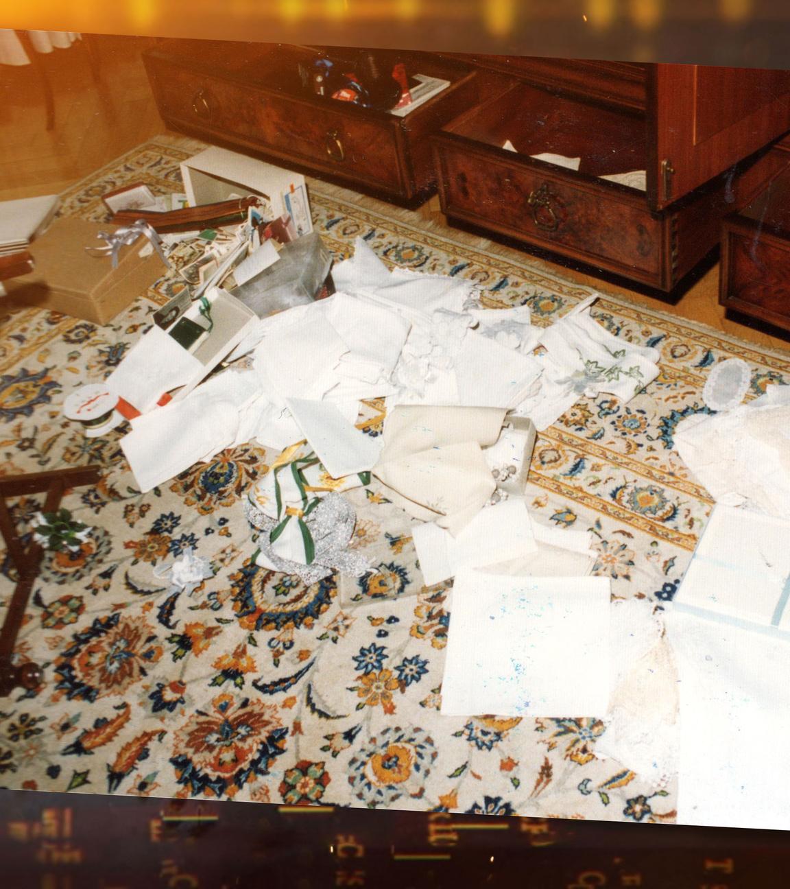 Papiere liegen vor einem Wohnzimmerschrank auf einem hellen, geblümten Teppich.