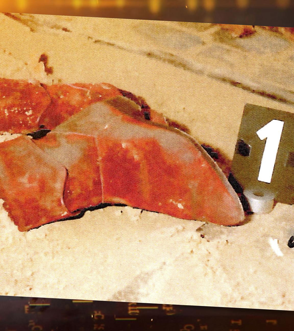 Tatortfoto: In einem Sandkasten liegt ein Paar rote Stiefel, daneben steht ein schwarzes Schild mit einer weißen Nummer "1". Den Sandkasten umgibt graues Kopfsteinpflaster, es ist teilweise ebenfalls mit Sand bedeckt. Oberhalb der Stiefel auf dem Kopfsteinpflasterst liegt, schemenhaft zu erkennen, ein Schal mit einer schwarze Tafel mit der weißen Nummer "4". An der Seite steht eine schwarze Tafel mit der Nummer "5" auf den Pflastersteinen.