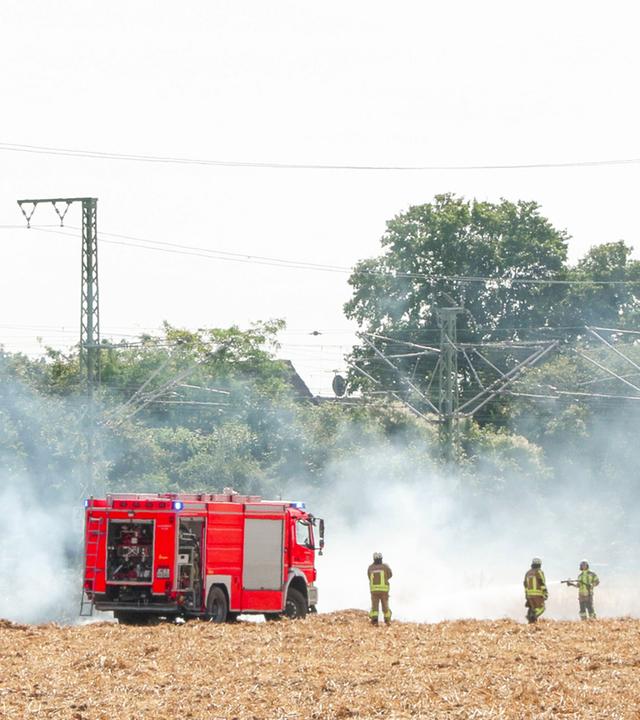 10.07.2026, Nordrhein-Westfalen, Langenfeld: Feuerwehrleute bei Löscharbeiten an einer Bahnstrecke.