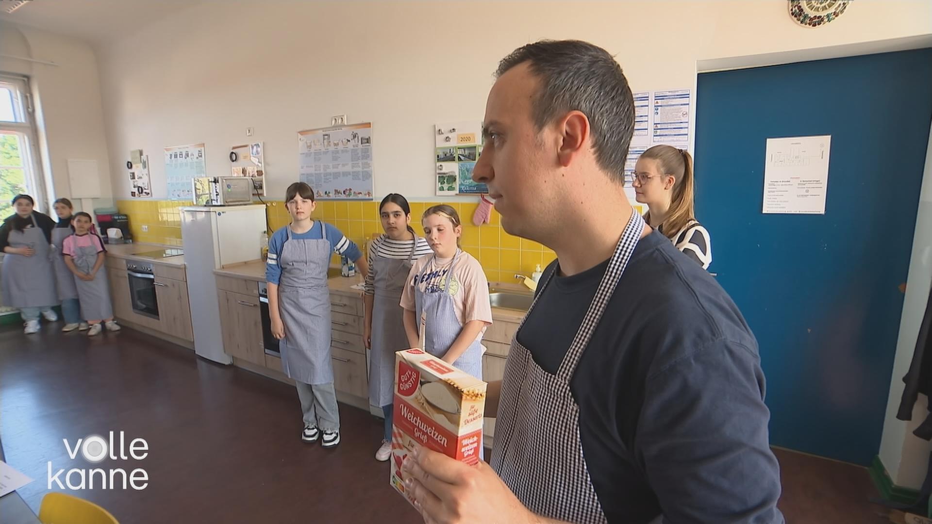 Lehrer steht mit Weizenmehl vor Kindern