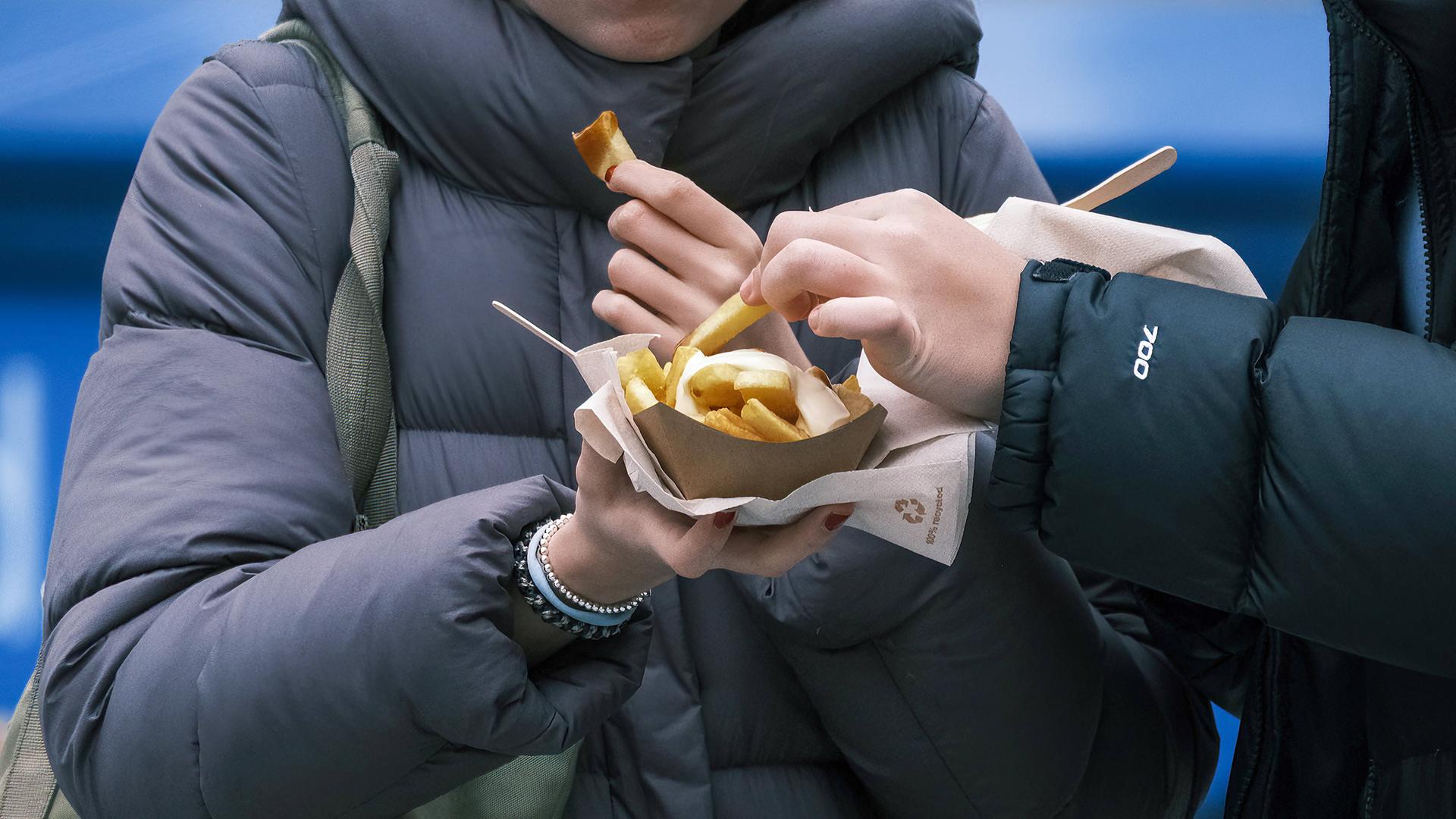 Junge Frauen essen Pommes mit Mayonnaise an einer Imbissbude