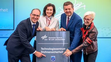 Alexander Dobrindt (l-r, CSU), Bundesminister des Innern, Dorothee Bär (CSU), Bundesministerin für Forschung, Technologie und Raumfahrt, Sven Schulze (CDU), Ministerpräsident von Sachsen-Anhalt, und Anke Kaysser-Pyzalla, Vorstandsvorsitzende vom Deutschen Zentrum für Luft- und Raumfahrt (DLR), eröffnen das Technologiezentrum für Drohnensicherheit und präsentieren die Stele mit dem Schriftzug der Einrichtung.
