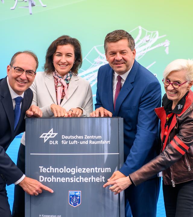 Alexander Dobrindt (l-r, CSU), Bundesminister des Innern, Dorothee Bär (CSU), Bundesministerin für Forschung, Technologie und Raumfahrt, Sven Schulze (CDU), Ministerpräsident von Sachsen-Anhalt, und Anke Kaysser-Pyzalla, Vorstandsvorsitzende vom Deutschen Zentrum für Luft- und Raumfahrt (DLR), eröffnen das Technologiezentrum für Drohnensicherheit und präsentieren die Stele mit dem Schriftzug der Einrichtung.