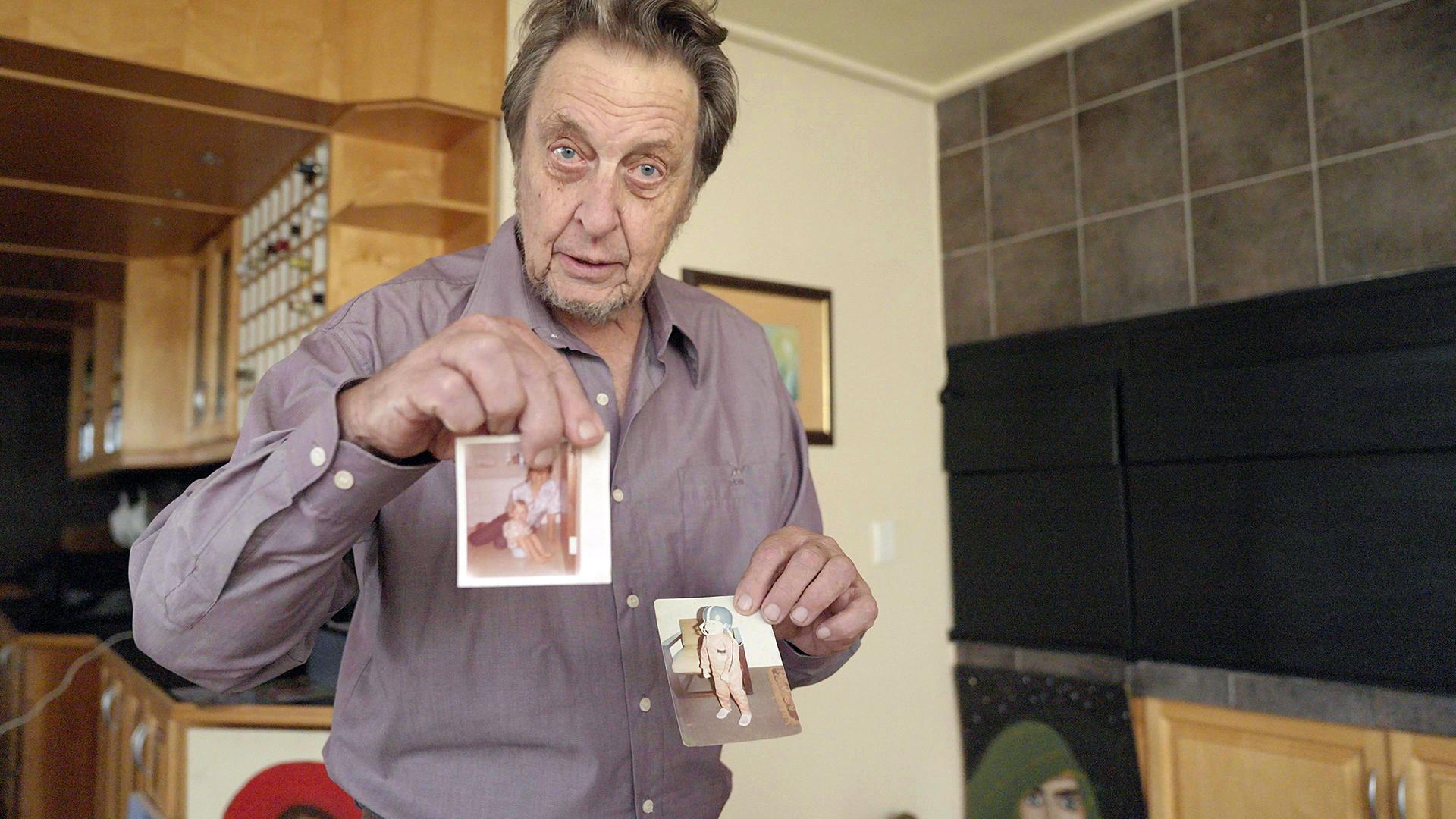 Errol Musk, ein 78-jähriger Mann, schaut in die Kamera und zeigt zwei Kinderfotos seines Sohnes Elon Musk.