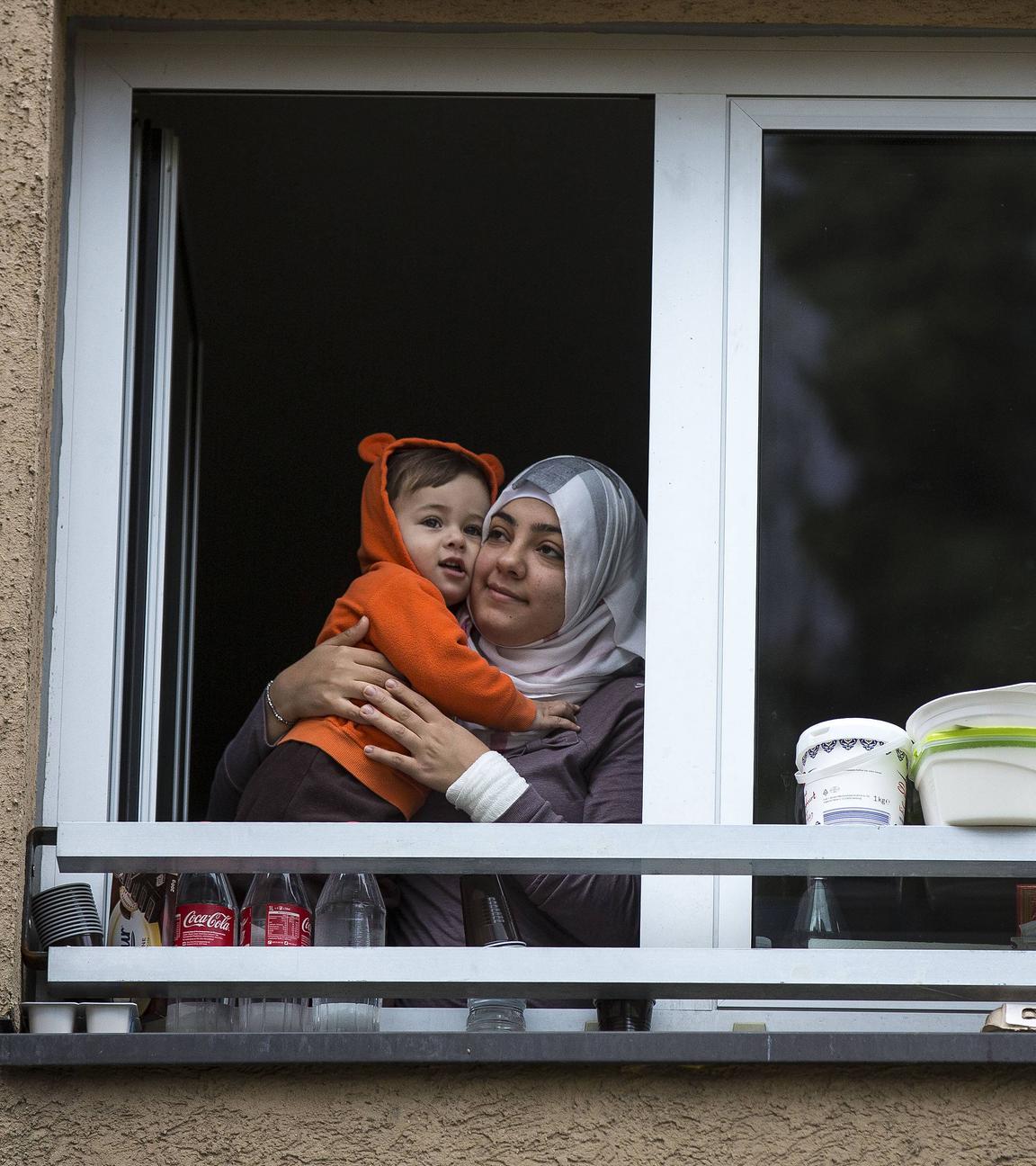 Frau Mutter mit Kind (Flüchtlinge aus dem Irak) schauen aus einem Fenster der Erstaufnahmeeinrichtung in Wiesbaden