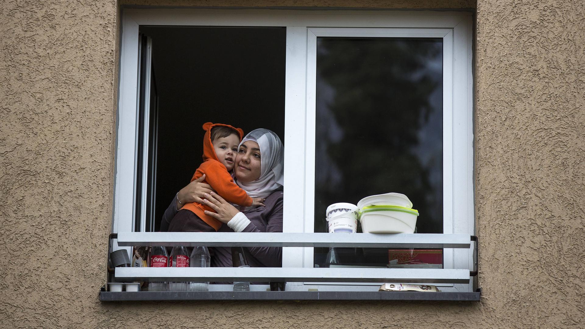 Frau Mutter mit Kind (Flüchtlinge aus dem Irak) schauen aus einem Fenster der Erstaufnahmeeinrichtung in Wiesbaden
