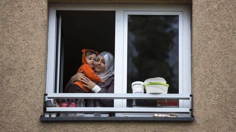 Frau Mutter mit Kind (Flüchtlinge aus dem Irak) schauen aus einem Fenster der Erstaufnahmeeinrichtung in Wiesbaden