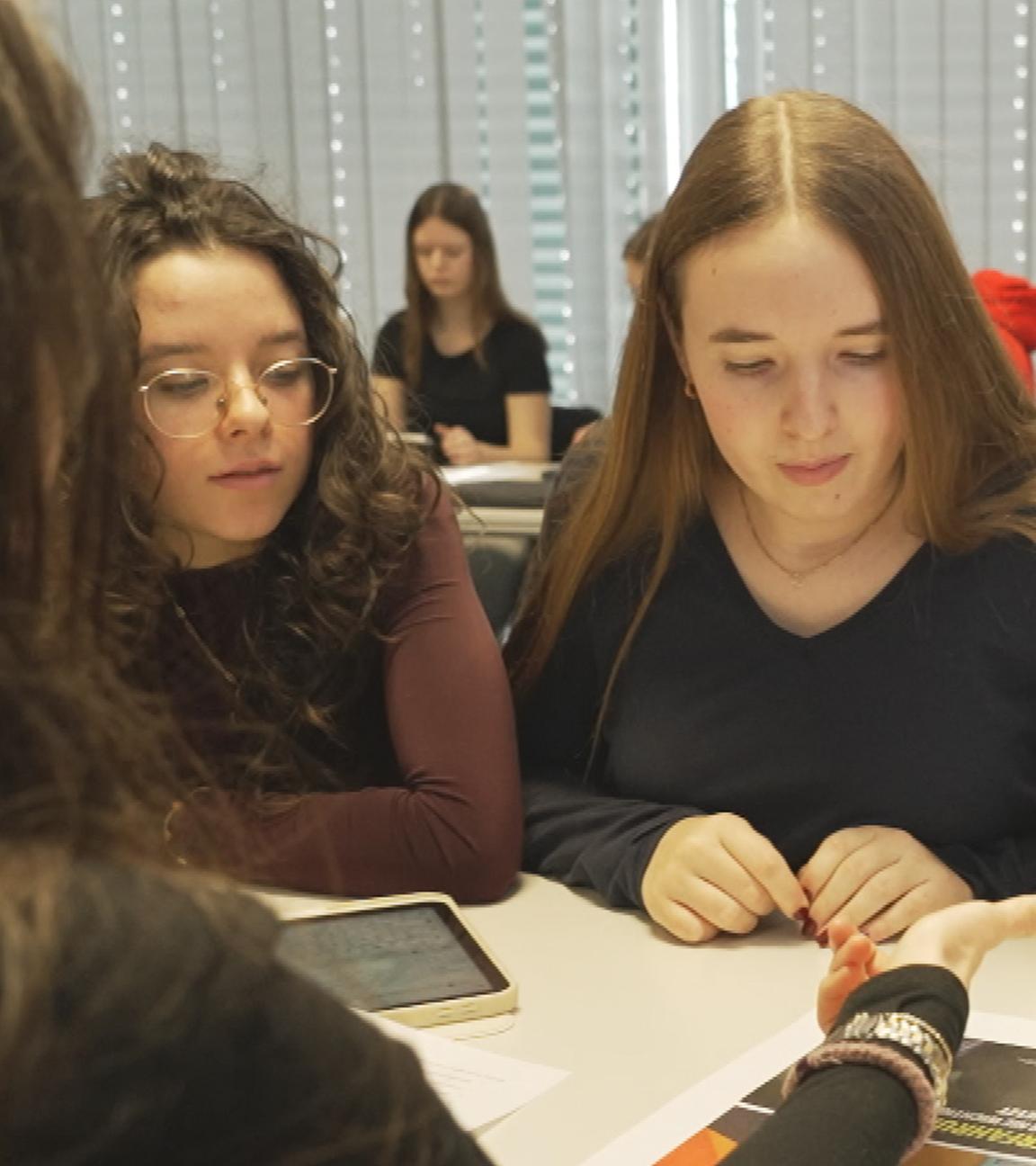 Junge Schülerinnen sitzen zusammen und unterhalten sich über anstehende Wahlen in Baden-Württemberg.