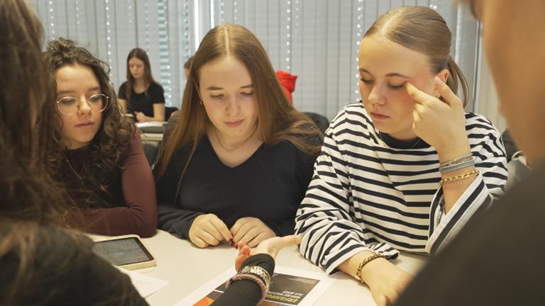 Junge Schülerinnen sitzen zusammen und unterhalten sich über anstehende Wahlen in Baden-Württemberg.