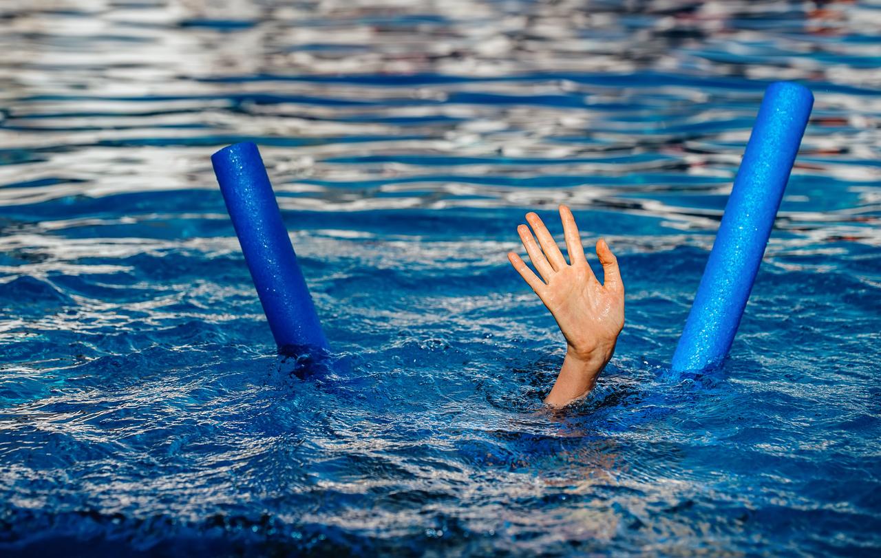 Die Hand eines ertrinkenden Kindes im Pool neben einer Poolnudel.