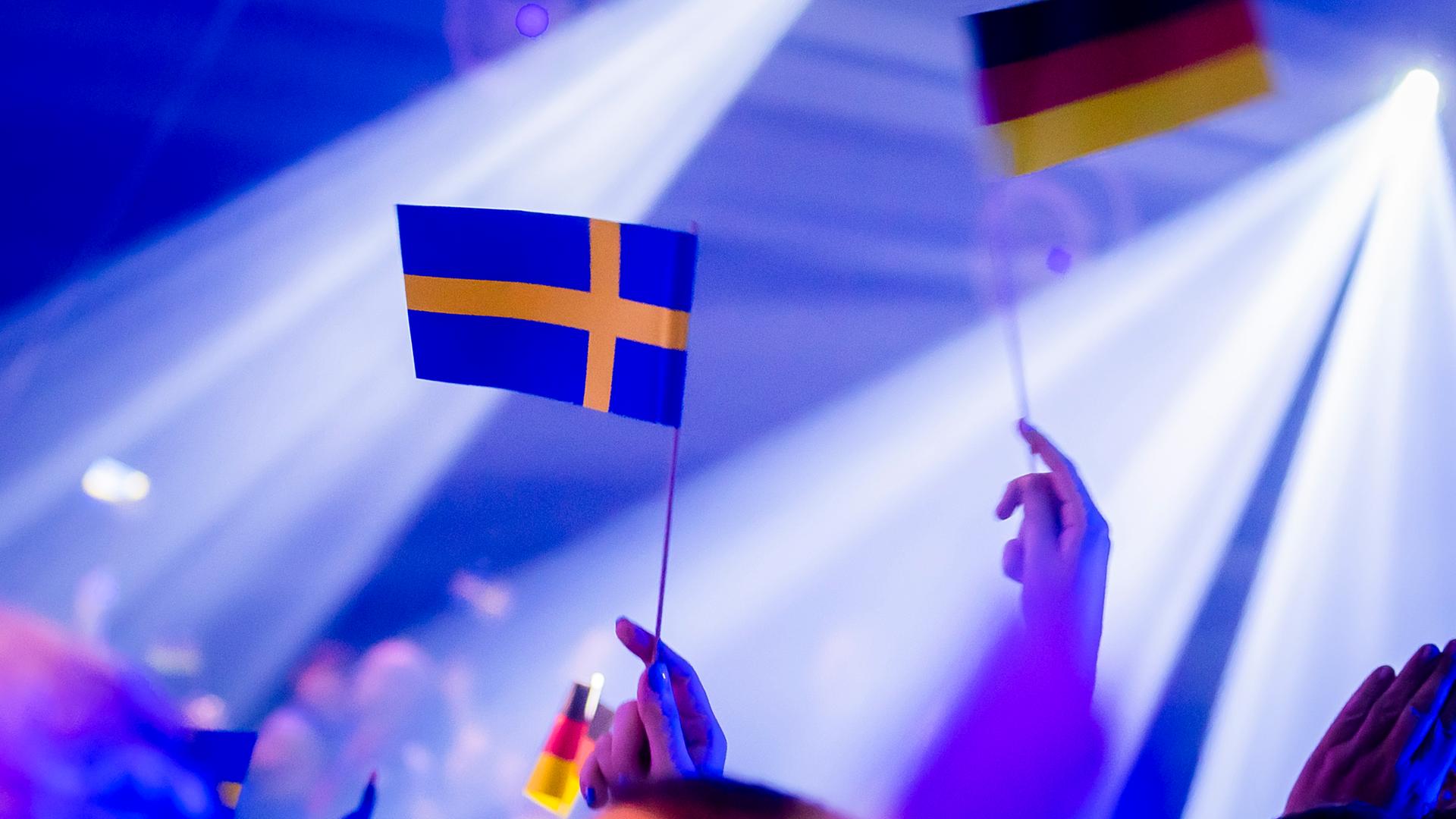 Zuschauer halten vor Beginn des Eurovision Song Contest - Das deutsche Finale 2024 die Fähnchen von Deutschland und Schweden hoch.