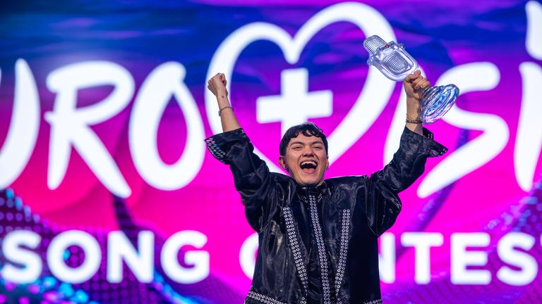 JJ aus Österreich, Gewinner des Eurovision Song Contest, hält während des großen Finales des 69. Eurovision Song Contest (ESC 2025) in der St. Jakobshalle auf der Bühne die Trophäe in der Hand und jubelt.