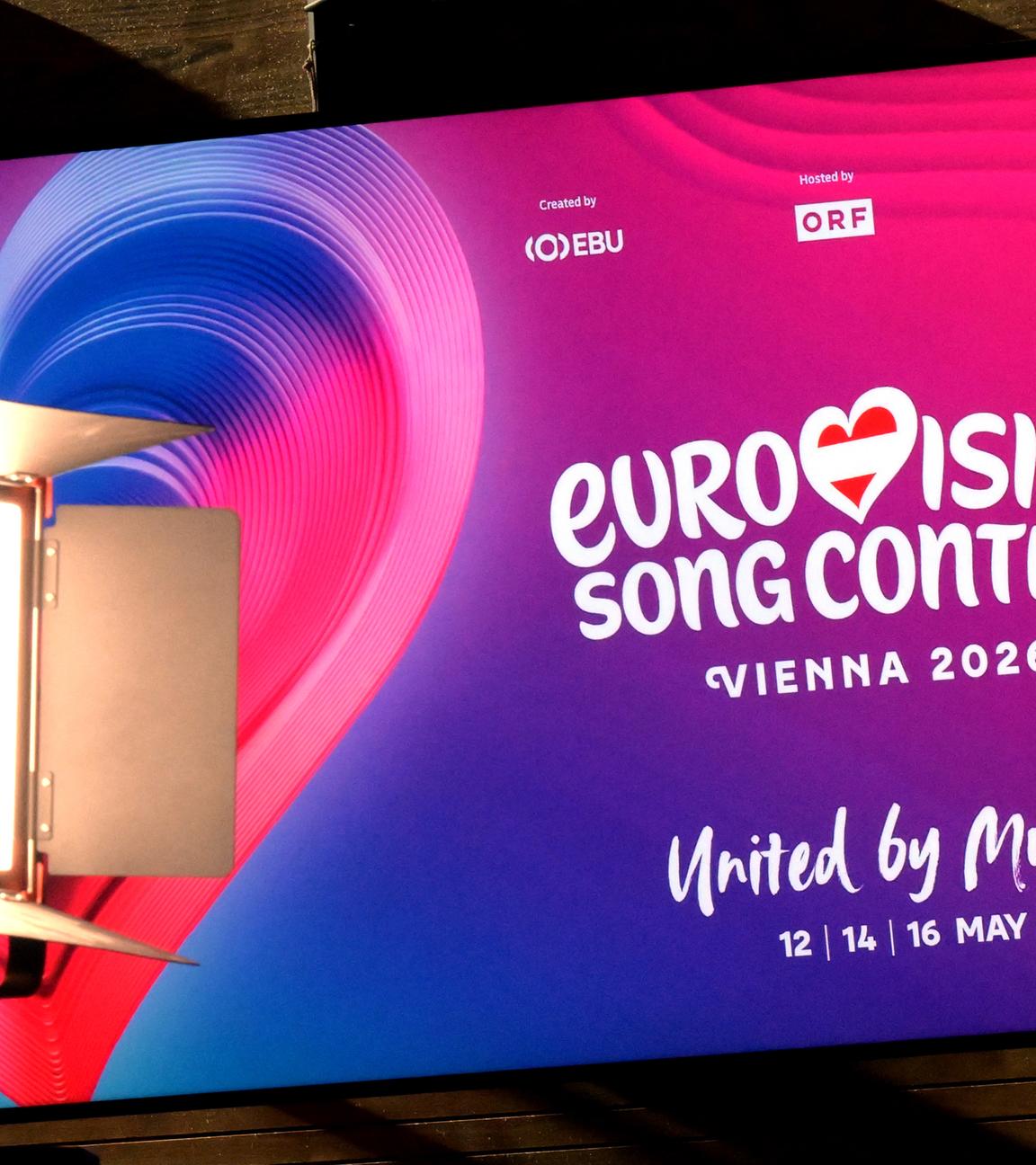Plakat mit Werbung für den Eurovision Song Contest 2026 in Wien mit Herz in pink-lila Farben.