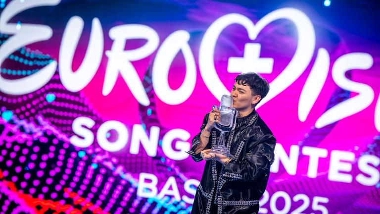 JJ aus Österreich, Gewinner des Eurovision Song Contest, hält während des großen Finales des 69. Eurovision Song Contest (ESC 2025) in der St. Jakobshalle auf der Bühne die Trophäe in der Hand und jubelt.
