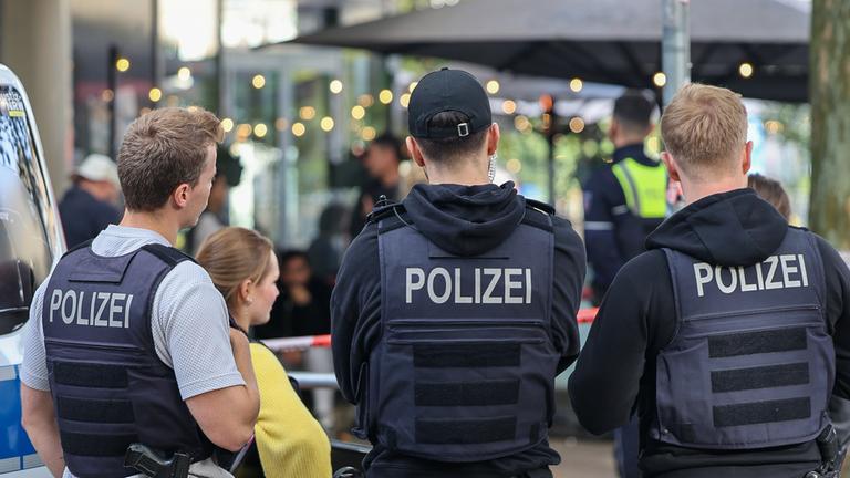 Nordrhein-Westfalen, Essen: Polizisten stehen vor einem Absperrband.