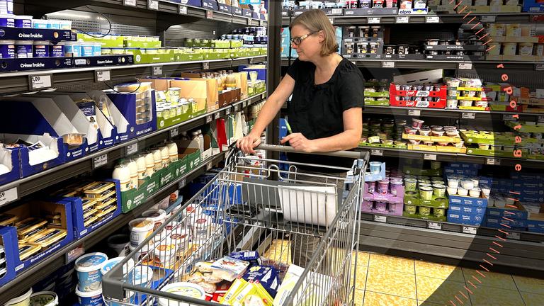 Friederike Pflaum steht mit einem Einkaufswagen vor dem Kühlregal im Supermarkt.