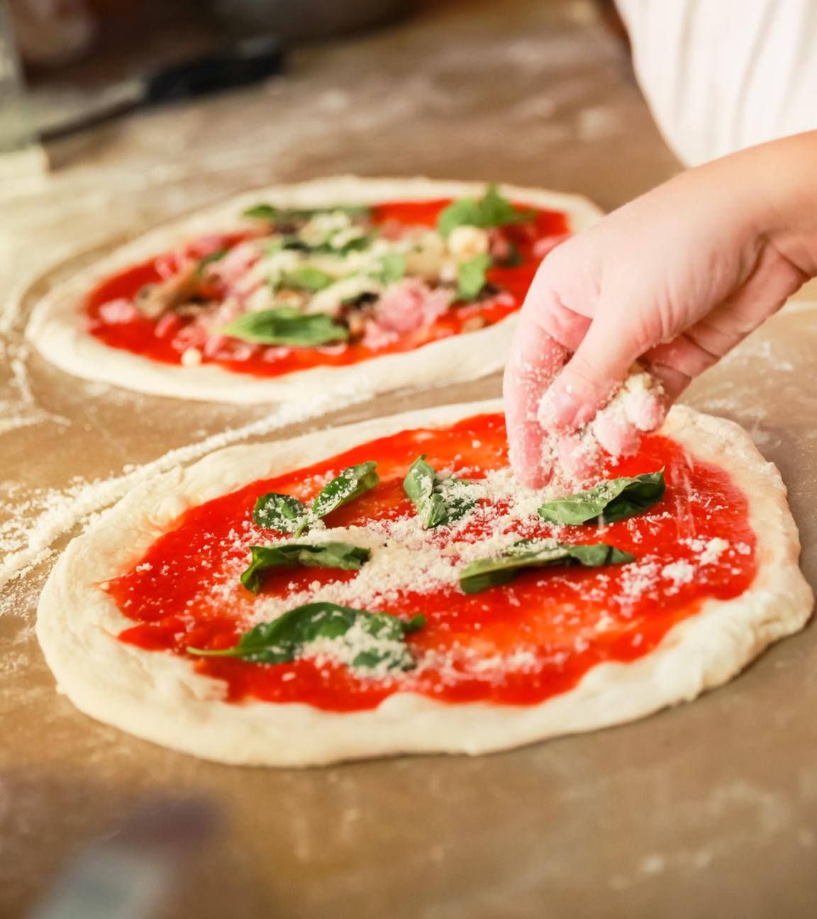 Man sieht eine Pizza, die gerade zubereitet wird. 