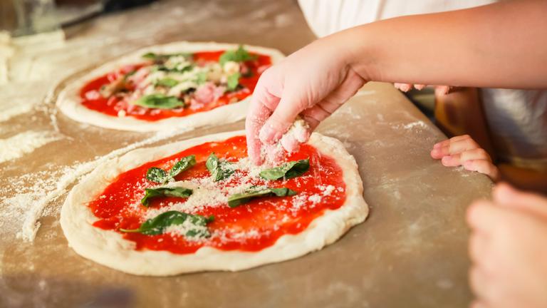 Man sieht eine Pizza, die gerade zubereitet wird. 