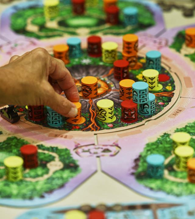 Menschen spielen auf der Publikumsmesse "Spiel Essen" das Brettspiel Kilauea.