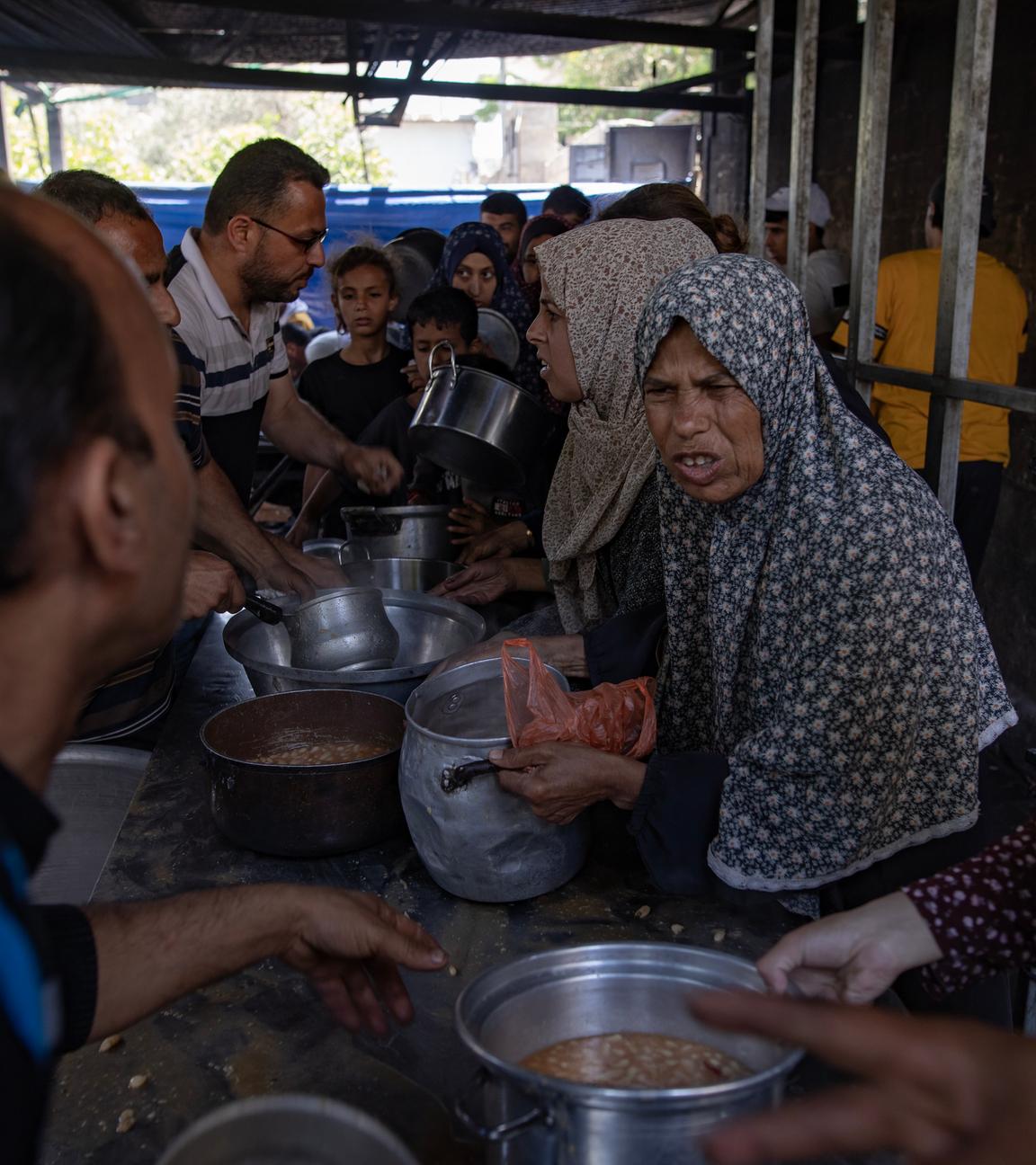 Menschen in Gaza holen sich Nahrung an einer Lebensmittelausgabe