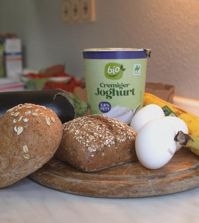 verschiedene gesunde Lebensmittel (Vollkornbrot, Bio-Joghurt, Eier, Banane) im Bild