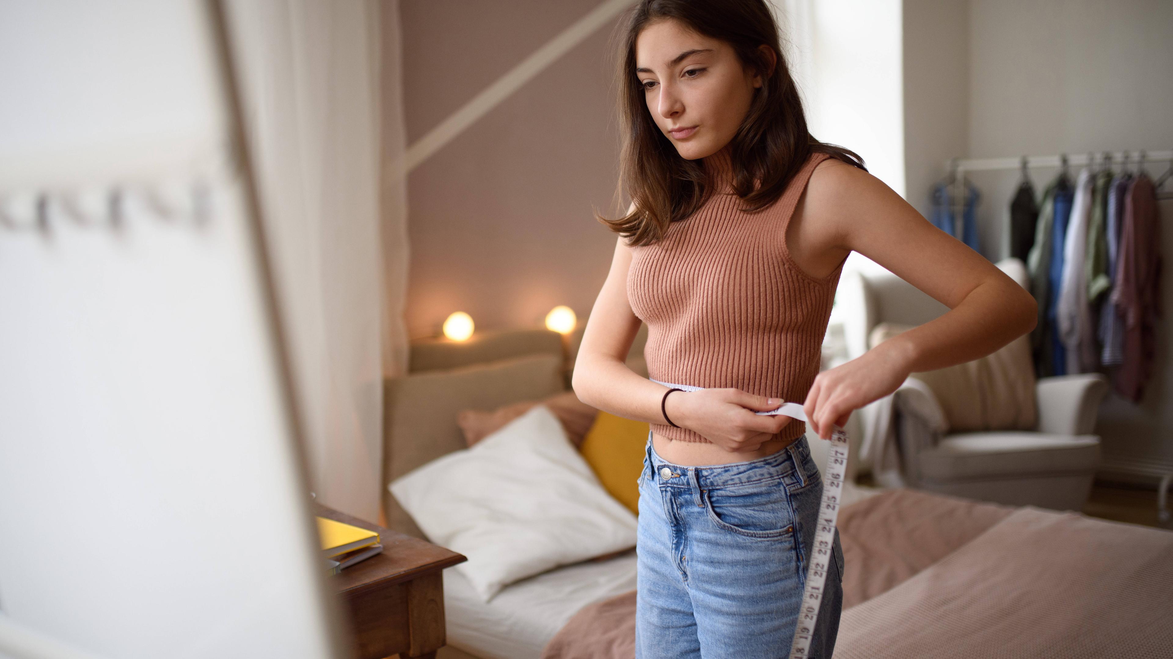 Junges Teenager-Mädchen schaut in ihrem Zimmer in den Spiegel.