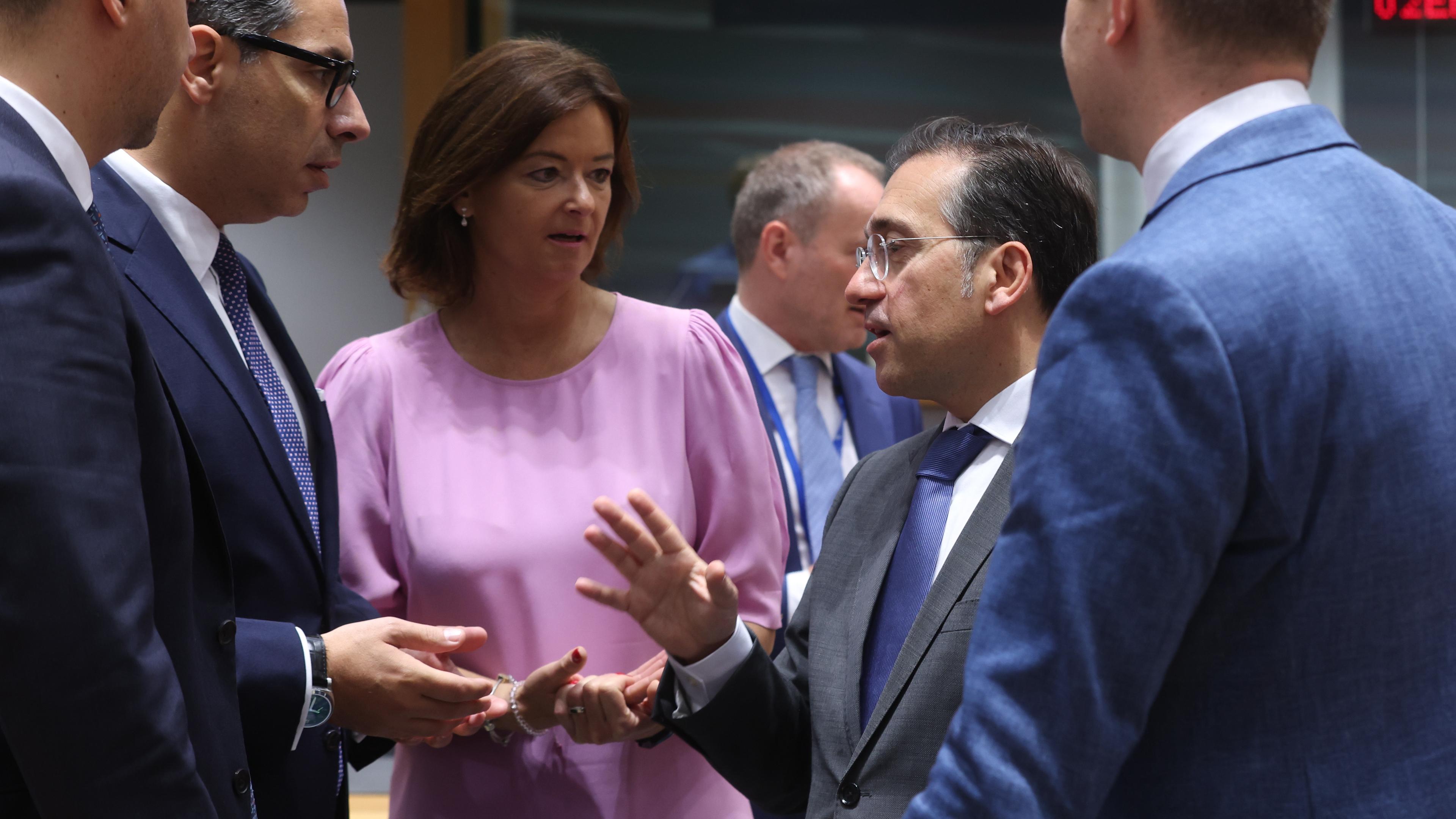 Mehrere europäische Außenminister*innen stehen im Kreis und reden miteinander. Sie gestikulieren.