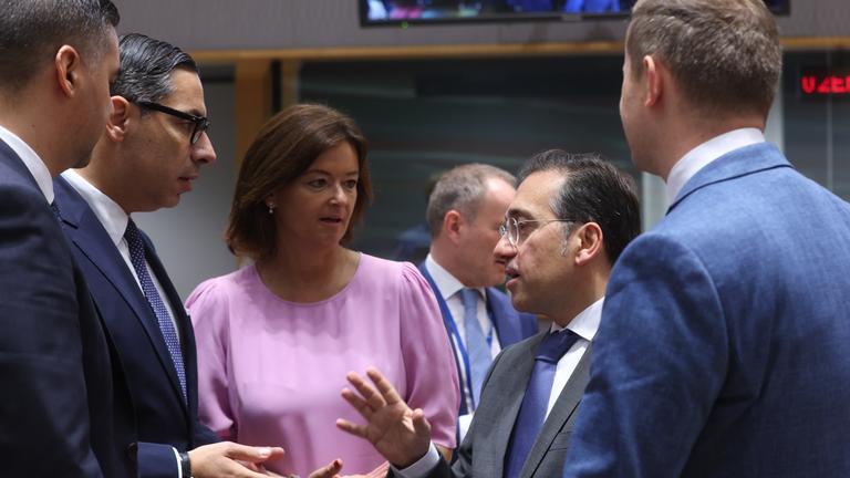 Mehrere europäische Außenminister*innen stehen im Kreis und reden miteinander. Sie gestikulieren.