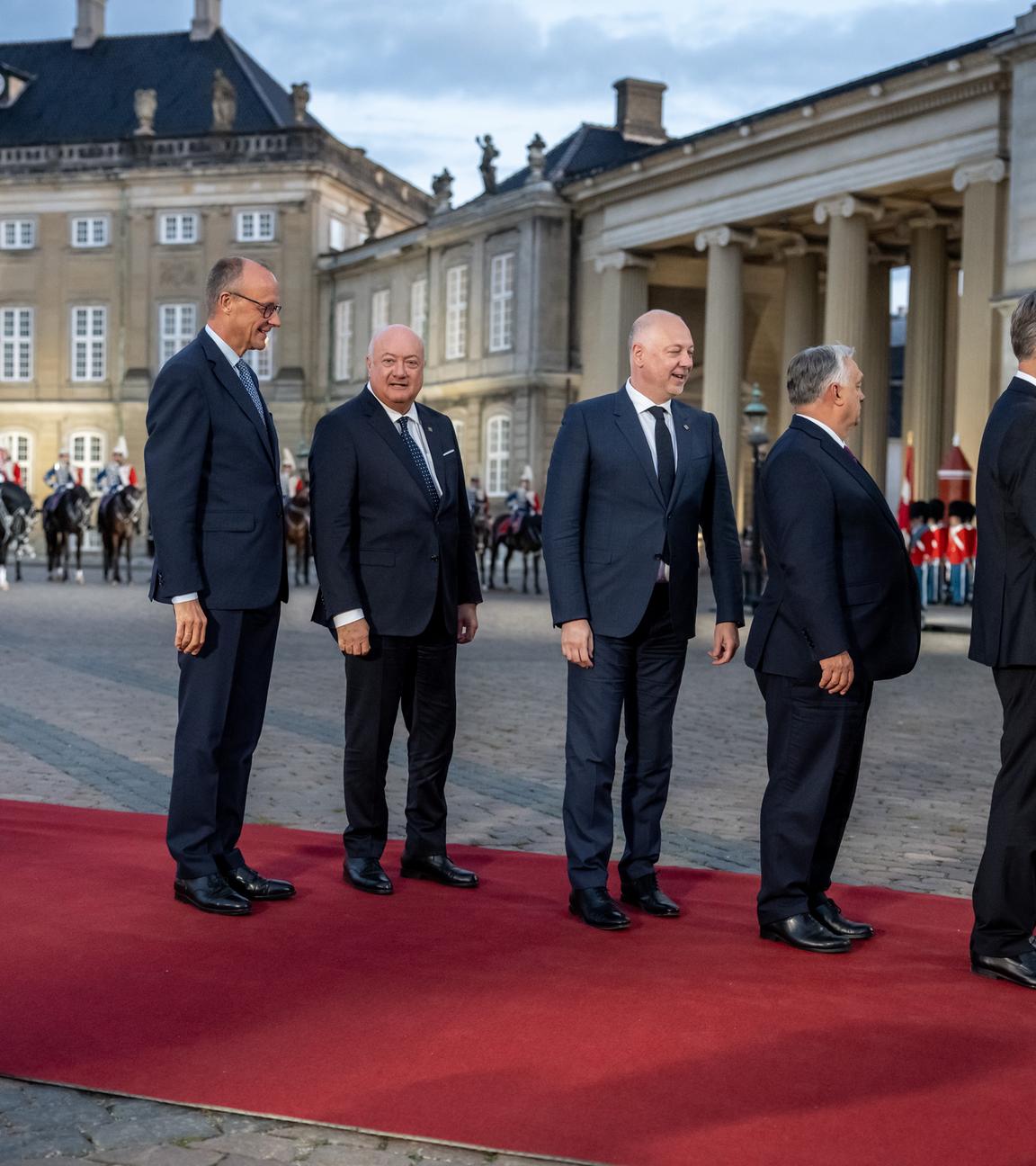 Bundeskanzler Friedrich Merz (CDU, l) kommt zum Abendessen am Schloss Amalienborg im Rahmen des informellen Treffens der EU-Staats- und Regierungschefs an und wartet mit anderen Gästen auf seine Begrüßung.