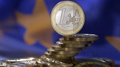 Euro-Münzen vor EU-Flagge