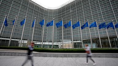  Die Flaggen der Europäischen Union wehen im Wind, während Fußgänger an der Zentrale der EU-Kommission vorbeigehen.