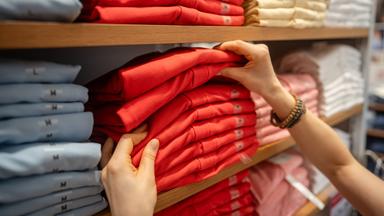 Eine Frau wählt Kleidung in einem Modegeschäft aus.