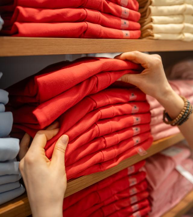 Eine Frau wählt Kleidung in einem Modegeschäft aus.