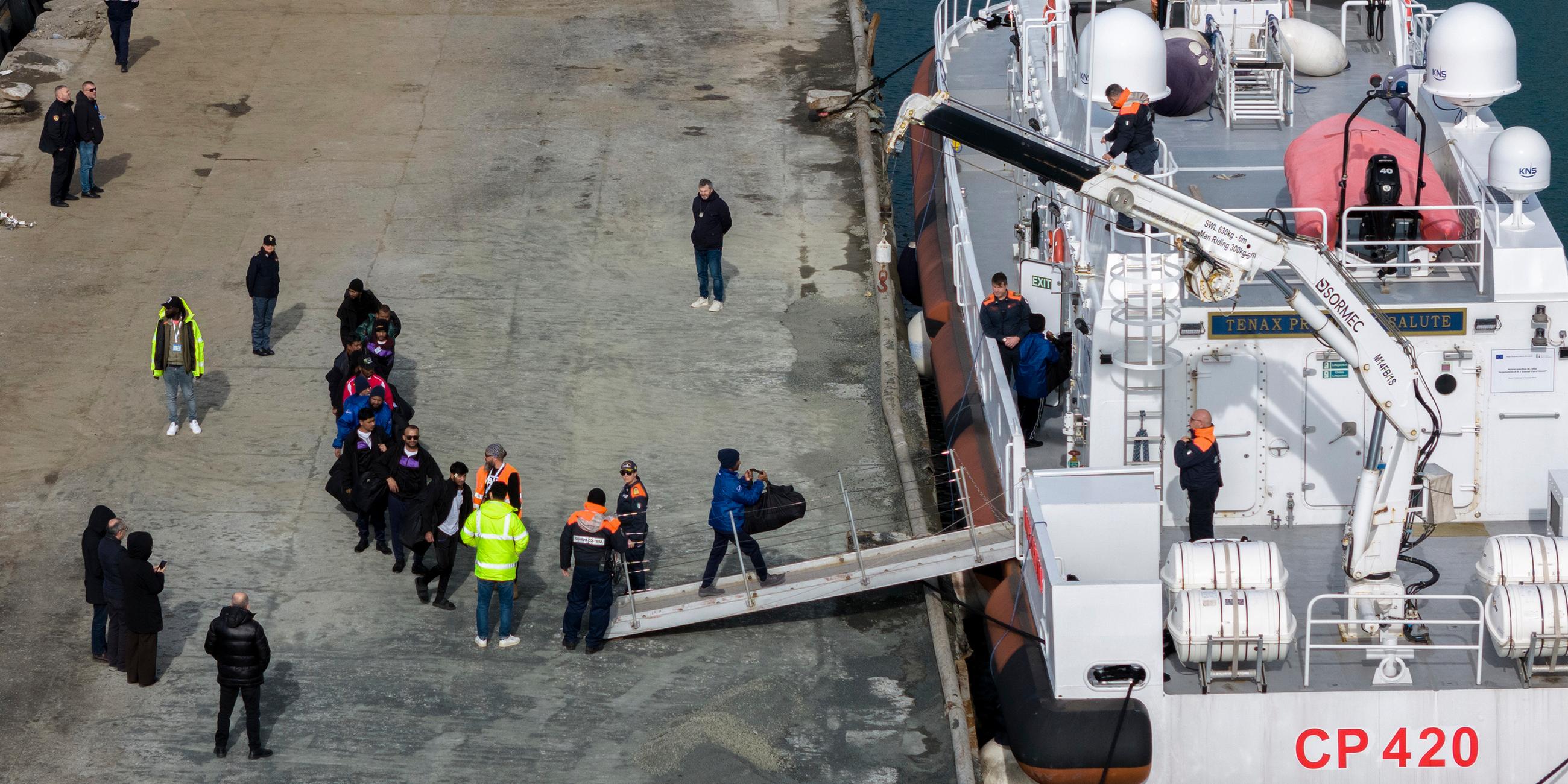 Migranten besteigen im Hafen von Shengjin im Nordwesten Albaniens ein Schiff der italienischen Küstenwache.