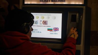 Eine Person kauft Fahrkarten an einem Automaten, auf dem angegeben ist, welche Euro-Banknoten und -Münzen akzeptiert werden, da das Land der Euro-Währungsunion beitritt.
