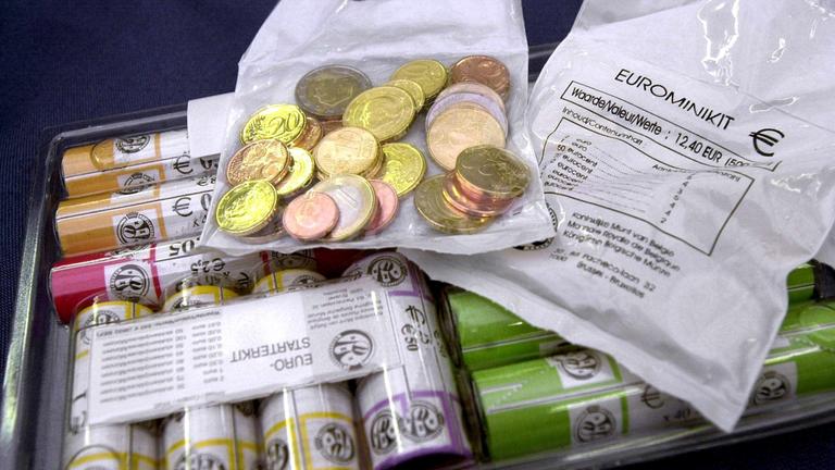 Mehrere Tüten mit Geldmünzen und Packungen mit Geldscheinen, die als Euro-Starterkit herausgegeben wurden.
