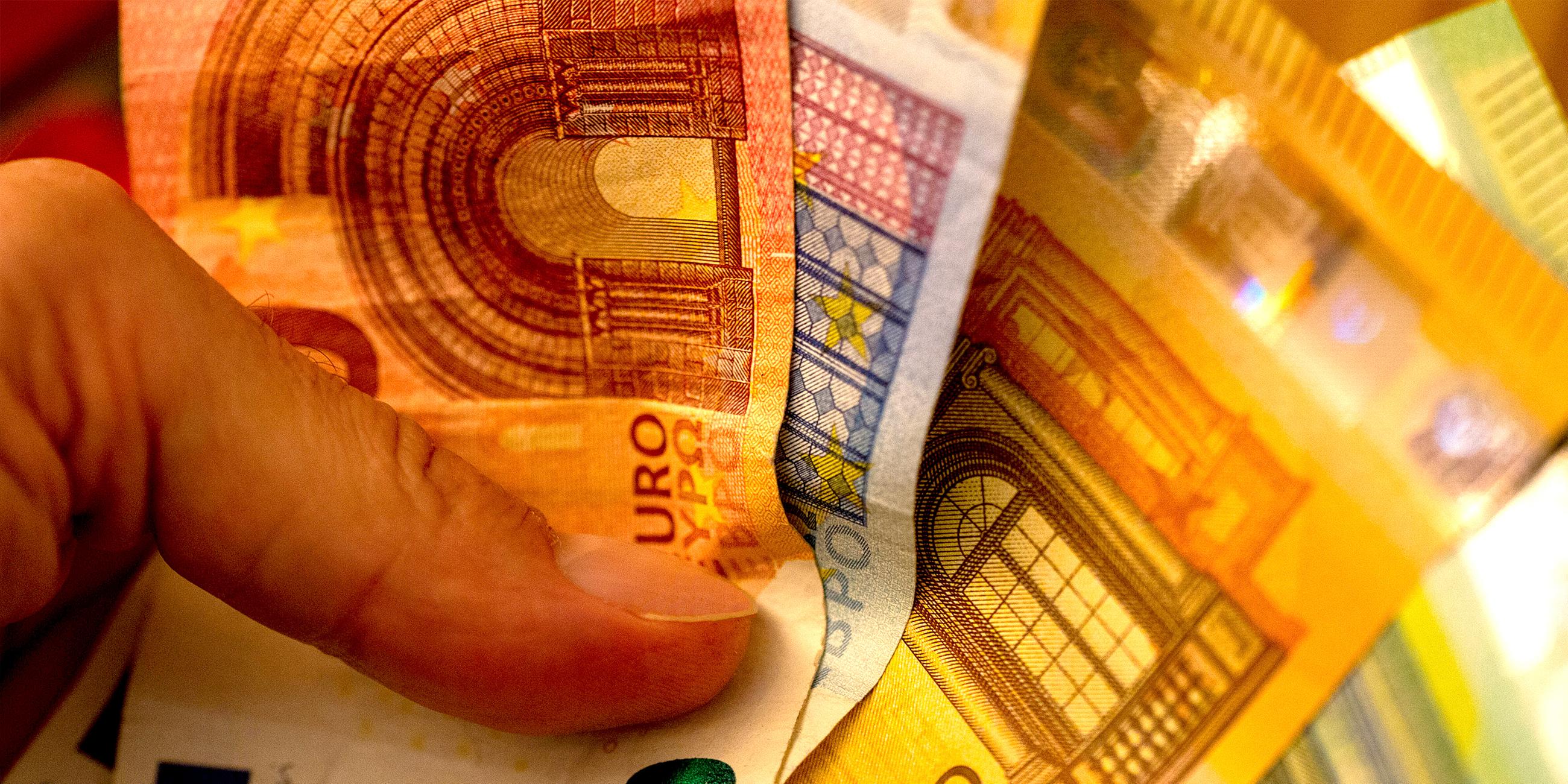 Ein Mann hält einen Bündel mit Eurobanknoten zur Bezahlung in der Hand