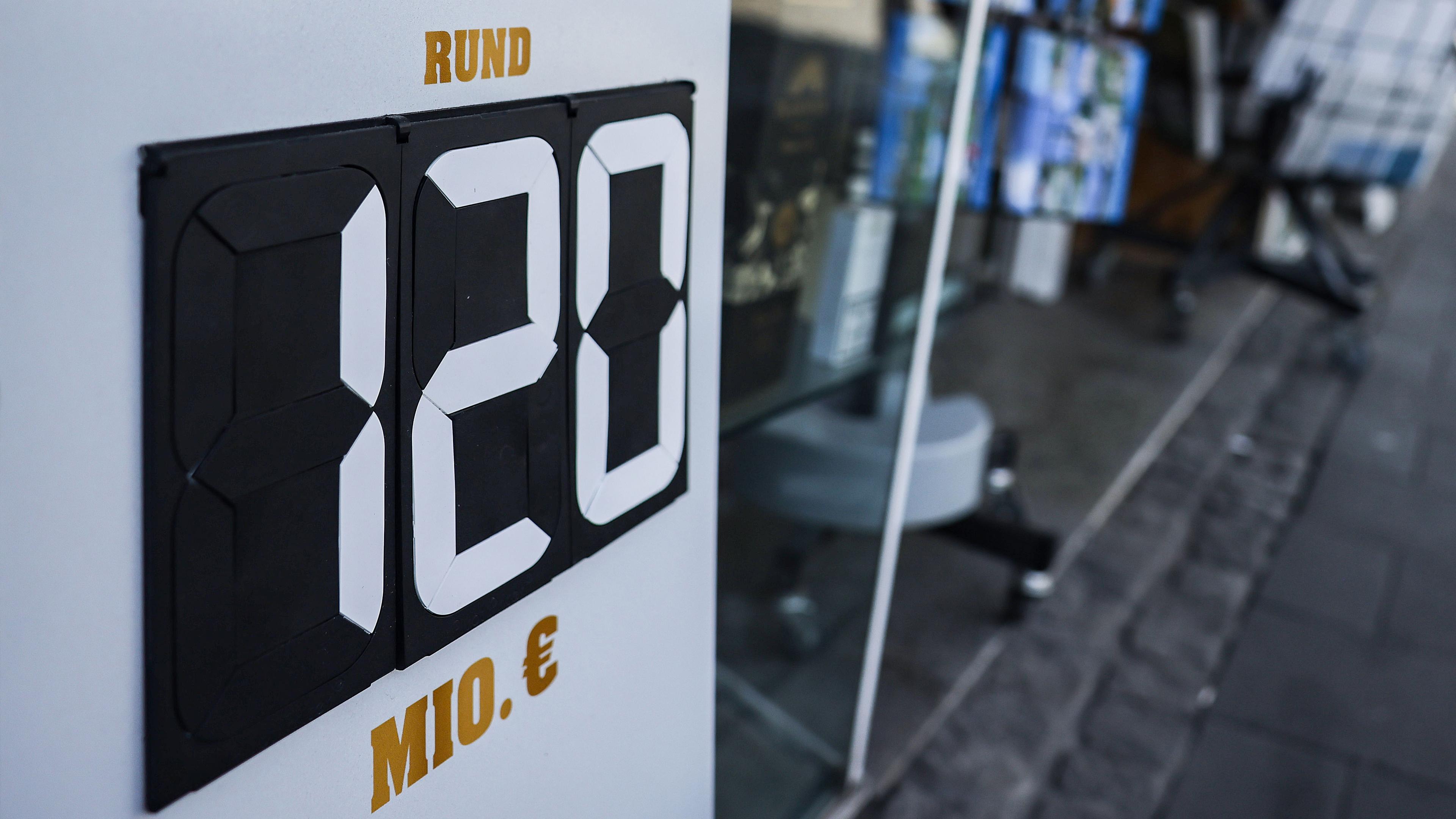 Ein Schild mit der Aufschrift "rund 120 Millionen Euro" steht vor einem Tabak- und Zeitschriften-Geschäft in Düsseldorf