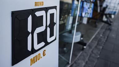 Ein Schild mit der Aufschrift "rund 120 Millionen Euro" steht vor einem Tabak- und Zeitschriften-Geschäft in Düsseldorf