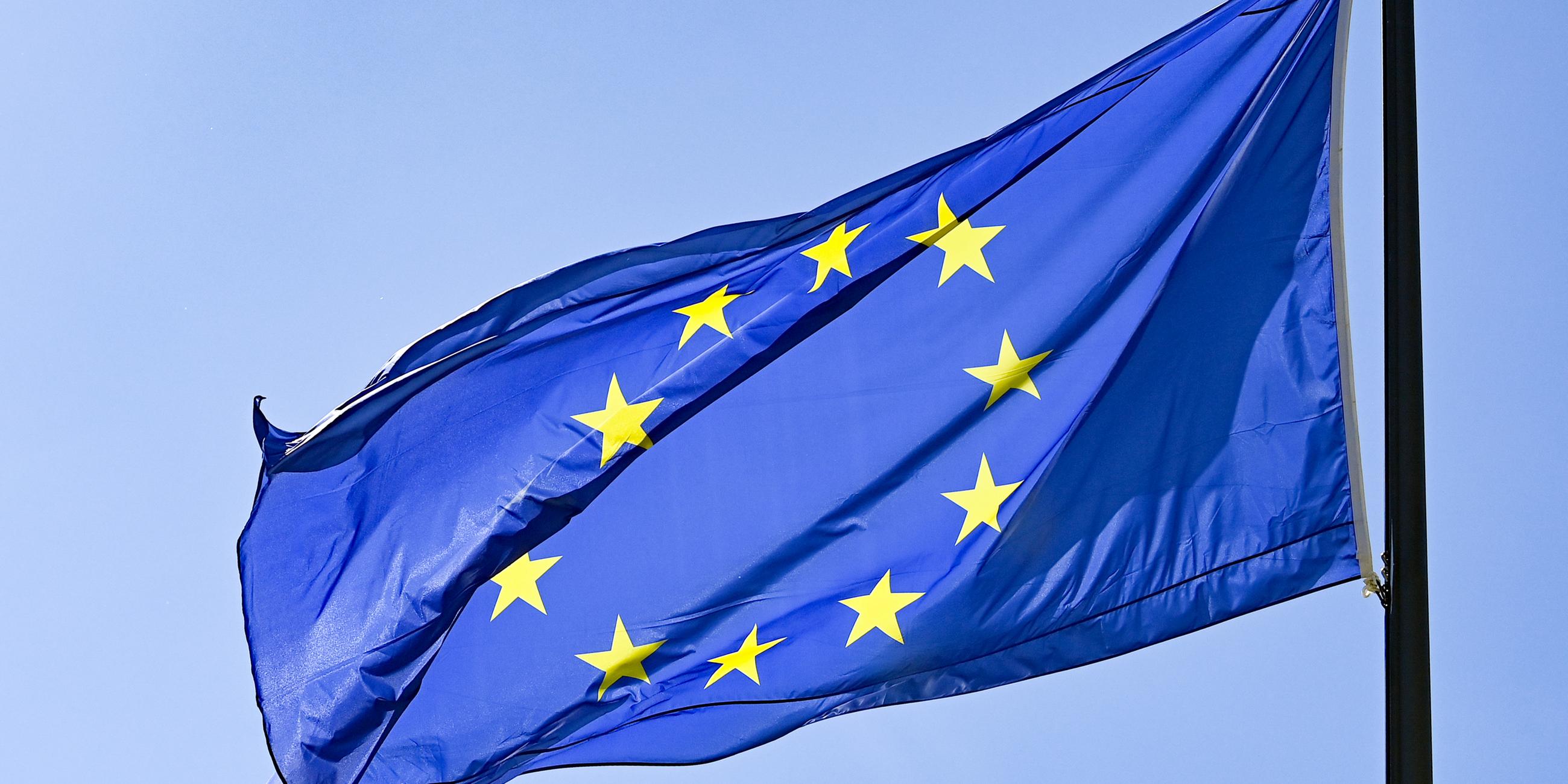 Die Europaflagge weht vor blauem Himmel. 
