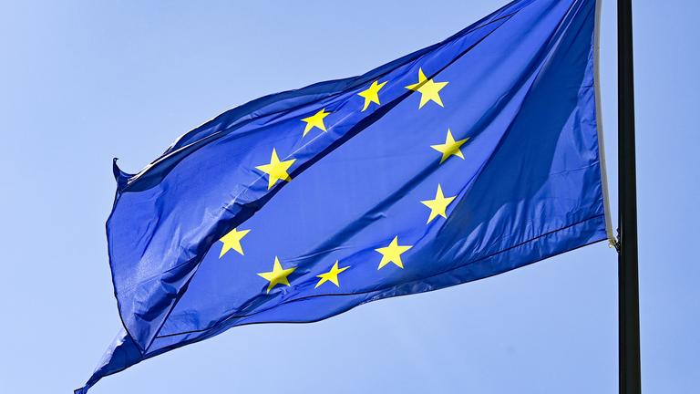 Die Europaflagge weht vor blauem Himmel. 