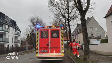 Eine Rettungskraft rennt zu einem Rettungswagen. Das Blaulicht ist an.