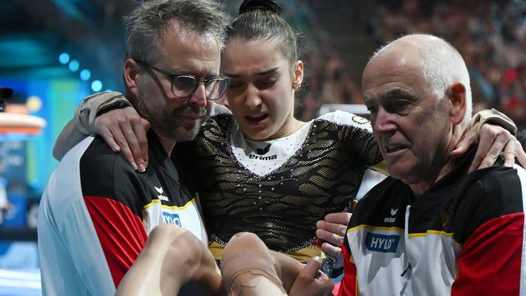 Helen Kevric (Mitte), wird am 29.05.2025 nach ihrer Übung am Sprung verletzt zur Seite getragen.