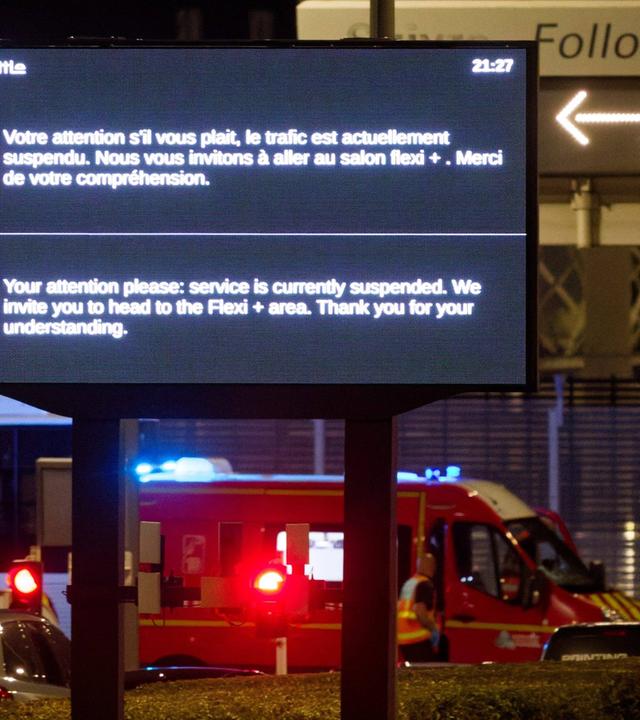 Ein Krankenwagen steht vor dem Eingang zum Eurotunnel. Auf einem Schild davor ist ein Warnhinweis zu lesen.